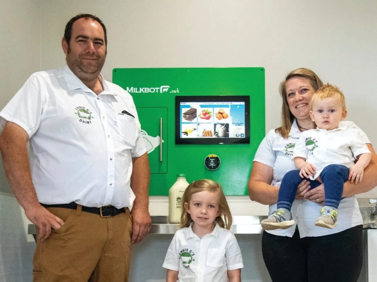 Annie+G's+Dairy+-+IMG-20250509-WA0000 Family-owned dairy business showcasing a Milkbot vending machine for fresh milk and dairy products, featuring the owners with their children, promoting local farming and sustainable practices.